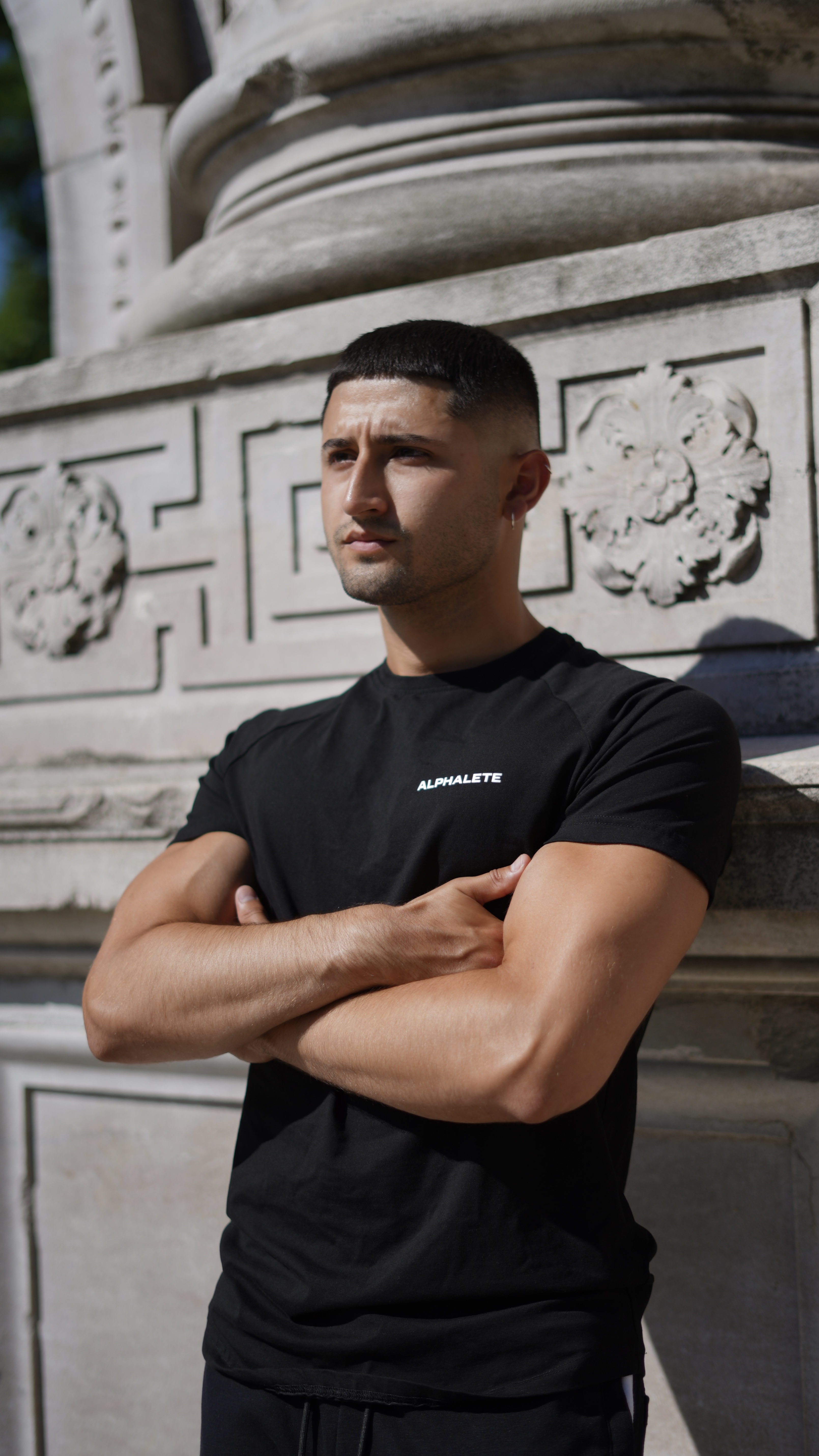 Coach Armando with arms crossed in front of building architecture